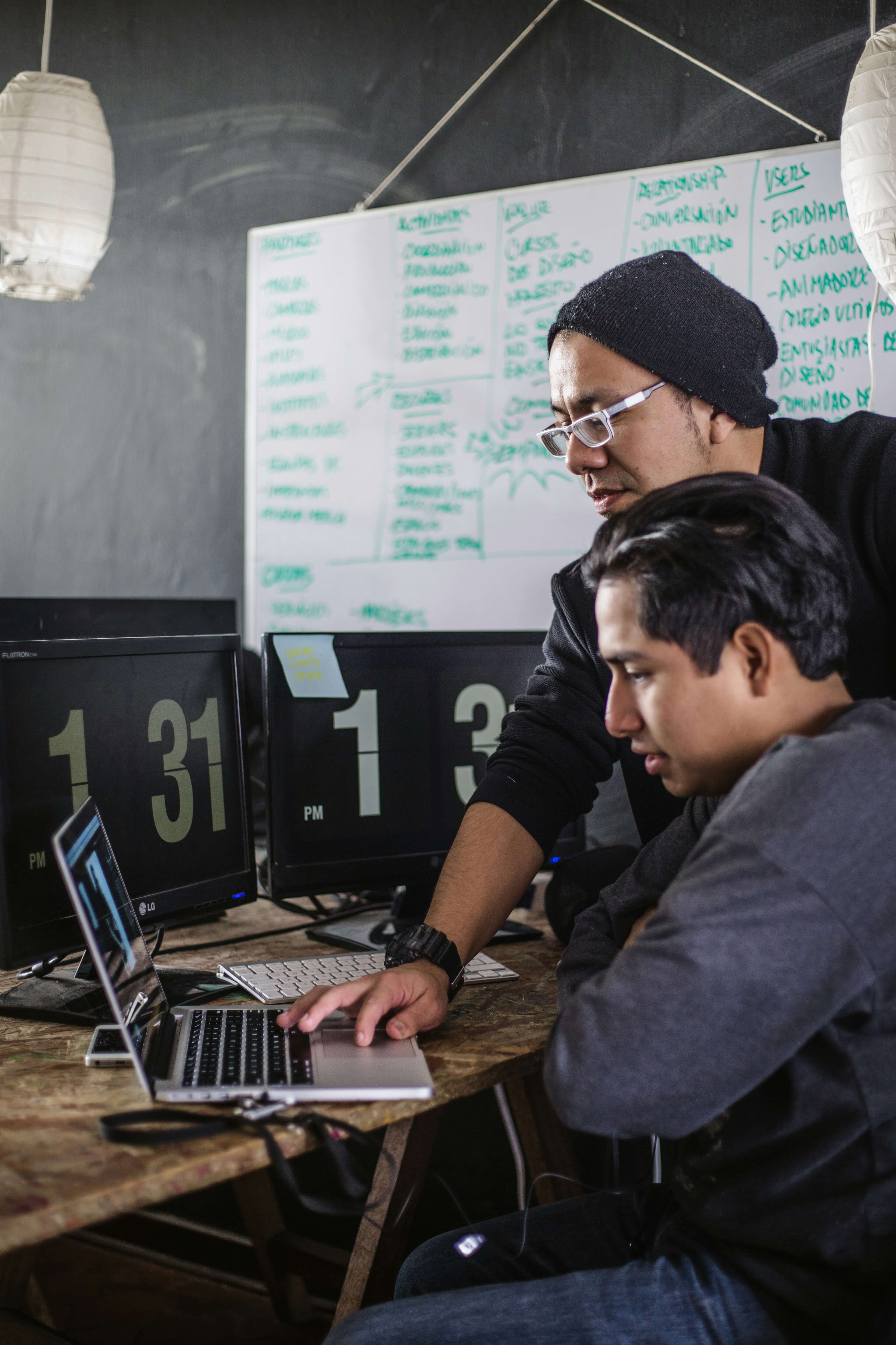 Twee jonge developers werken samen achter een laptop